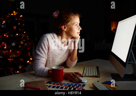 Female designer sitting in front of pc on xmas night Stock Photo