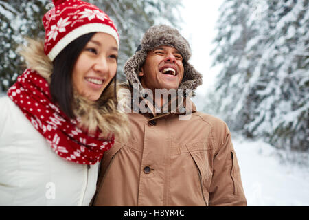 Funny guy in winter-cap and warm jacket laughing on wintery day in natural environment Stock Photo