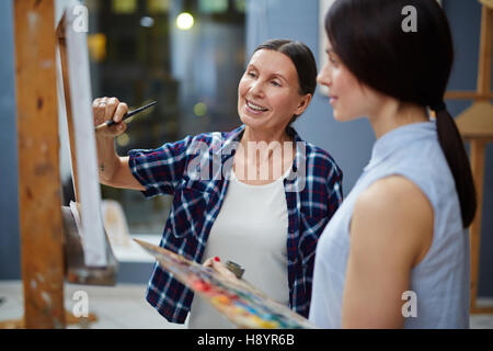 Experienced teacher of painting showing her student how to do it professionally Stock Photo