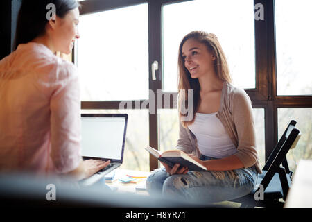 Two girls discussing homework after classes in cafe Stock Photo