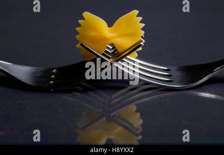 Pasta farfalle on a fork on black background Stock Photo