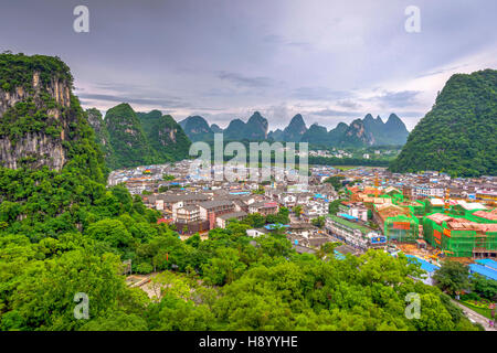 YANGSHUO, CHINA - JUNE 12: View over skyline of Yangshuo surrounded with recognizable karst landscape. Karst mountains are the biggest tourist attract Stock Photo