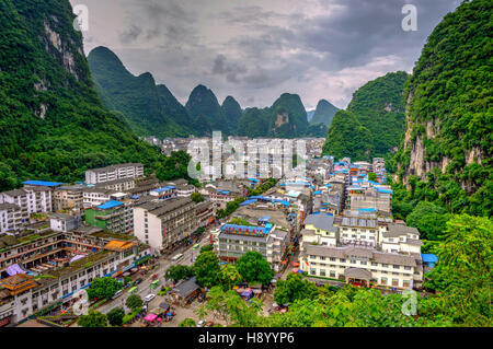 YANGSHUO, CHINA - JUNE 12: View over skyline of Yangshuo surrounded with recognizable karst landscape. Karst mountains are the biggest tourist attract Stock Photo