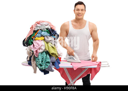 Joyful muscular guy ironing a pile of clothes isolated on white background Stock Photo