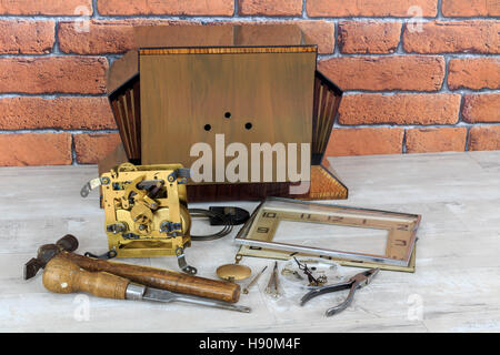 Vintage art deco wooden mantel clock in pieces with tools with old white brick wall effect background Stock Photo