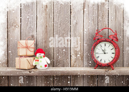 Christmas gift boxes, alarm clock and snowman toy in front of wooden wall. View with copy space Stock Photo