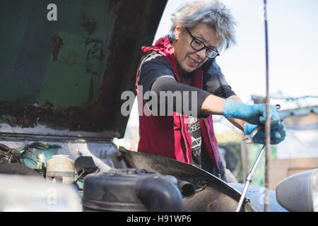 Elderly car mechanic working on her vintage car Stock Photo
