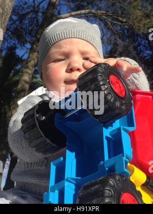 Baby boy playing with dump truck in the park a sunny winter morning Stock Photo
