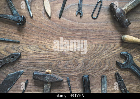 Different tools (pliers, hammer, wrench, nippers, chisel, rasp, screwdriver, drill) on a wooden background. Fathers day card with copy space. Stock Photo