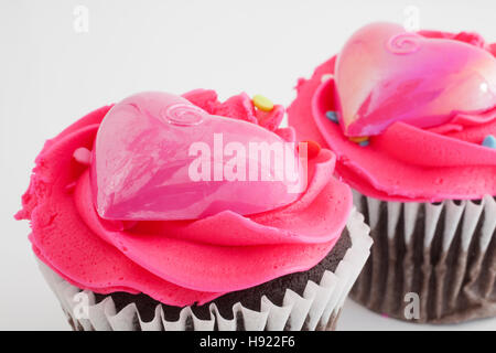 Two chocolate cupcakes with pink frosting and plastic hearts Stock Photo