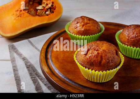 Homemade pumpkin muffins on the cutting board and butternut squash. Fall seasonal vegetable food. Thanksgiving homemade sweet pastry. Stock Photo