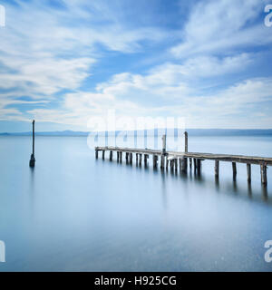 Wooden pier or jetty remains on a blue lake sunset. Long Exposure photography Stock Photo