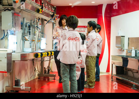 Japan, Nishinomiya, KidZania, Indoor childrens activity play park. Coke-Cola bottling plant, Japanese women teaching 4 children how to use machine. Stock Photo