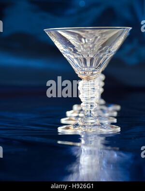 Row of empty cocktail glasses with reflection against blue background Stock Photo