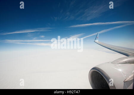 View from an airplane window seat crossing over the English channel, showing part of the engine and wing. Stock Photo