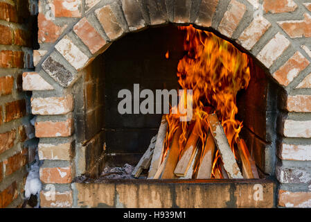 Fireplace with fire burning in daylight Stock Photo