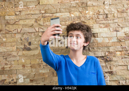 10 years old boy taking a selfie picture using a mobile phone camera Stock Photo