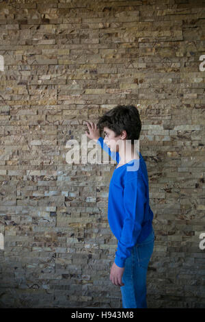 10 years old boy leaning against the wall looking away Stock Photo