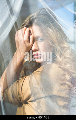Scared young woman hiding face with hand Stock Photo