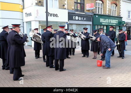 A passer-putting  some money into a Salvation Army band bucket. Stock Photo