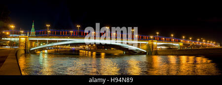 The view from Prechistenskaya embankment of moskva River on the Greater Stone Bridge in bright evening lights, reflecting in dark water, Moscow Stock Photo