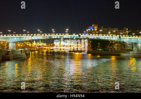 The night walk along the Moskva River with the view on bright illuminated Patriarshy and Greater Stone Bridges and the towers of Moscow Kremlin Stock Photo