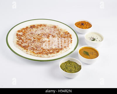 Onion uthappam in a plate served with sambar and three types of chutneys is a traditional south Indian tiffin on a white background Stock Photo