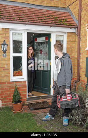 A young plumber/builder and a female householder talk as he leaves a private home after completing a job. Stock Photo
