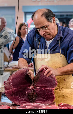 Worker in fish market cutting up a huge tuna fish with a huge knife Stock Photo