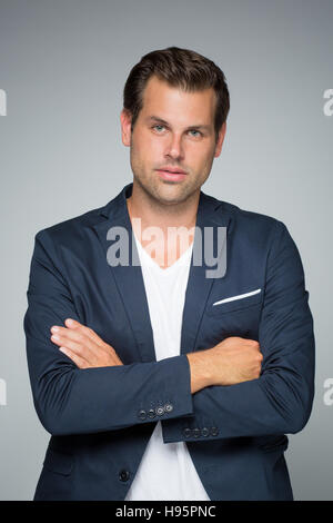Portrait of a smart young man standing with arms crossed. Stock Photo