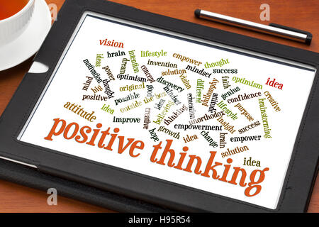 positive thinking and attitude word cloud on a digital tablet with a cup of tea Stock Photo