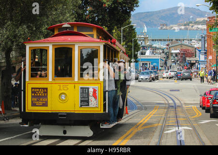 San Francisco, California - Mai 23, 2015: Lot Tourists riding on the iconic cable car, blue sky day at top of Hyde Street view overlooking the bay wat Stock Photo