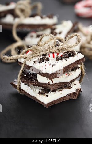 Dark and white chocolate peppermint bark stacked and tied together over a black background. Extreme shallow depth of field. Stock Photo