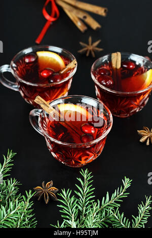 Red Christmas punch / drink with cinnamon, orange slices, anise and fresh cranberries over a dark background. Stock Photo