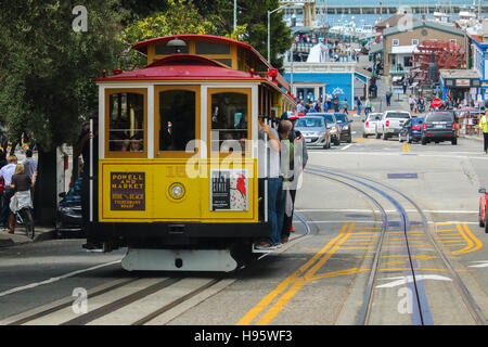 San Francisco, California - Mai 23, 2015: Tourists riding on the iconic cable car, blue sky day at top of Hyde Street view overlooking the bay water a Stock Photo
