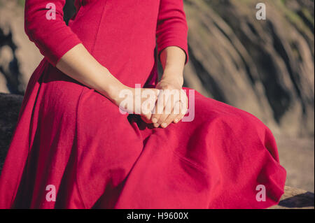 A young woman is sitting on the beach and is relaxing with her hands in her lap Stock Photo