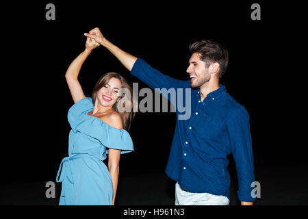 Cheerful young couple dancing and laughing on the beach at night Stock Photo