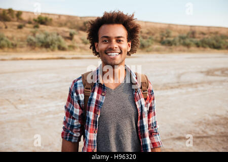 Portrait of cheerful african american young man in plaid shirt with backpack Stock Photo