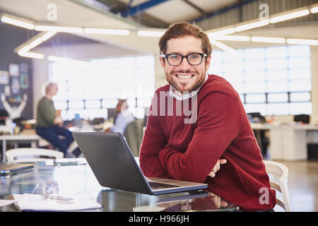 Portrait smiling businesswoman working at laptop in office Stock Photo