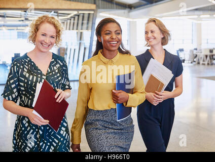 Smiling businesswomen walking in office Stock Photo