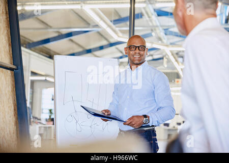 Businessman at flipchart leading meeting in conference room Stock Photo