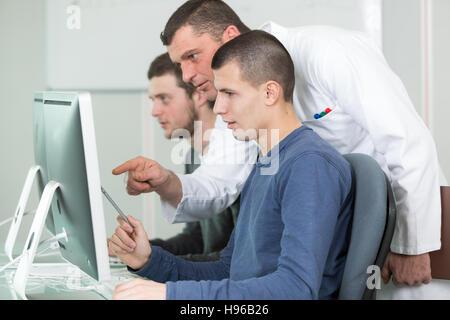tutor and young students in computing class Stock Photo