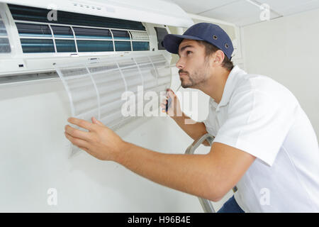 portrait of mid-adult male technician repairing air conditioner Stock Photo