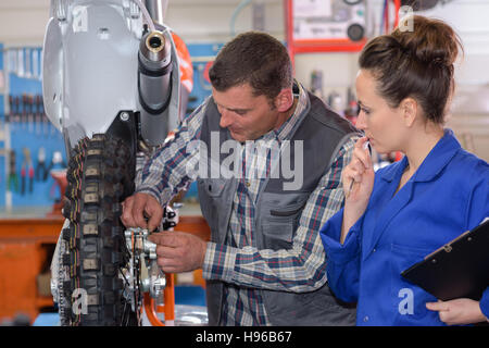 engineer and apprentice working on machine in factory Stock Photo