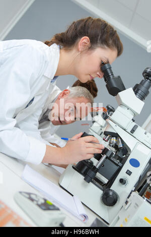 male and female scientists using microscopes in laboratory Stock Photo