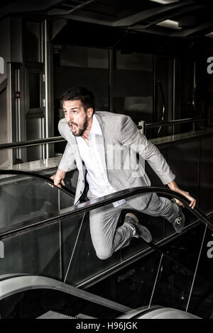 Businessman in Panic. Strong Young Man on Escalator. Stress Concept. Stock Photo