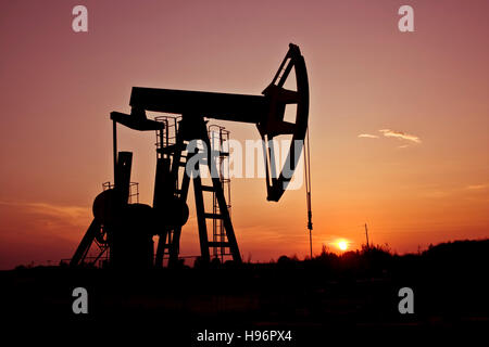 An industrial pumpjack in the sunset Stock Photo
