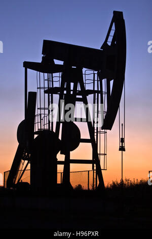 An industrial pumpjack in the sunset, silhouette Stock Photo