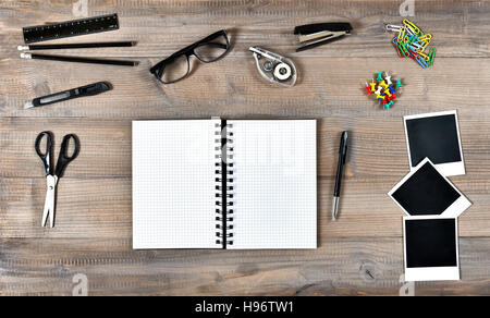 Office and school supplies over wooden background. Open book, photo frames and writing tools Stock Photo