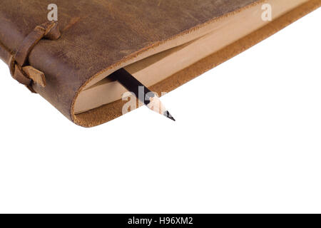 close up of a black pencil between the pages of a notebook with leather brown covers isolated on white Stock Photo